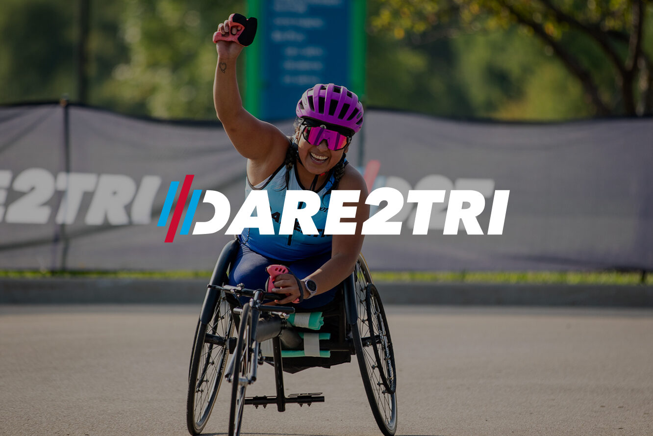 Dare2tri atlete with fist in air as she crosses the finish line of a race.